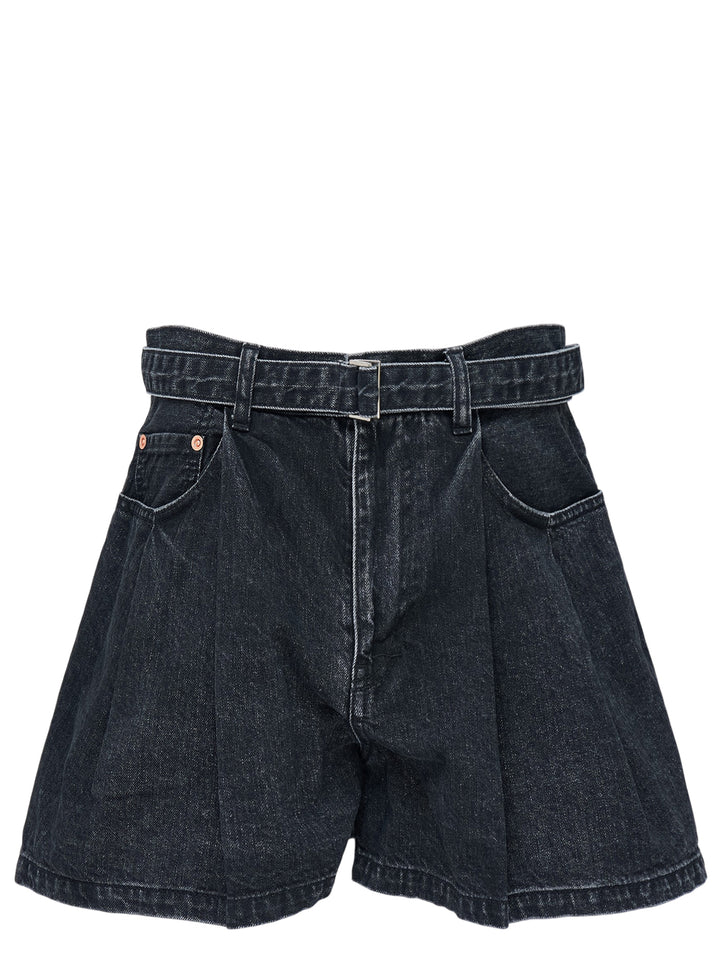 sacai belted wide-leg denim shorts in washed black with front pleats, contrast stitching, and an integrated metal-buckle belt