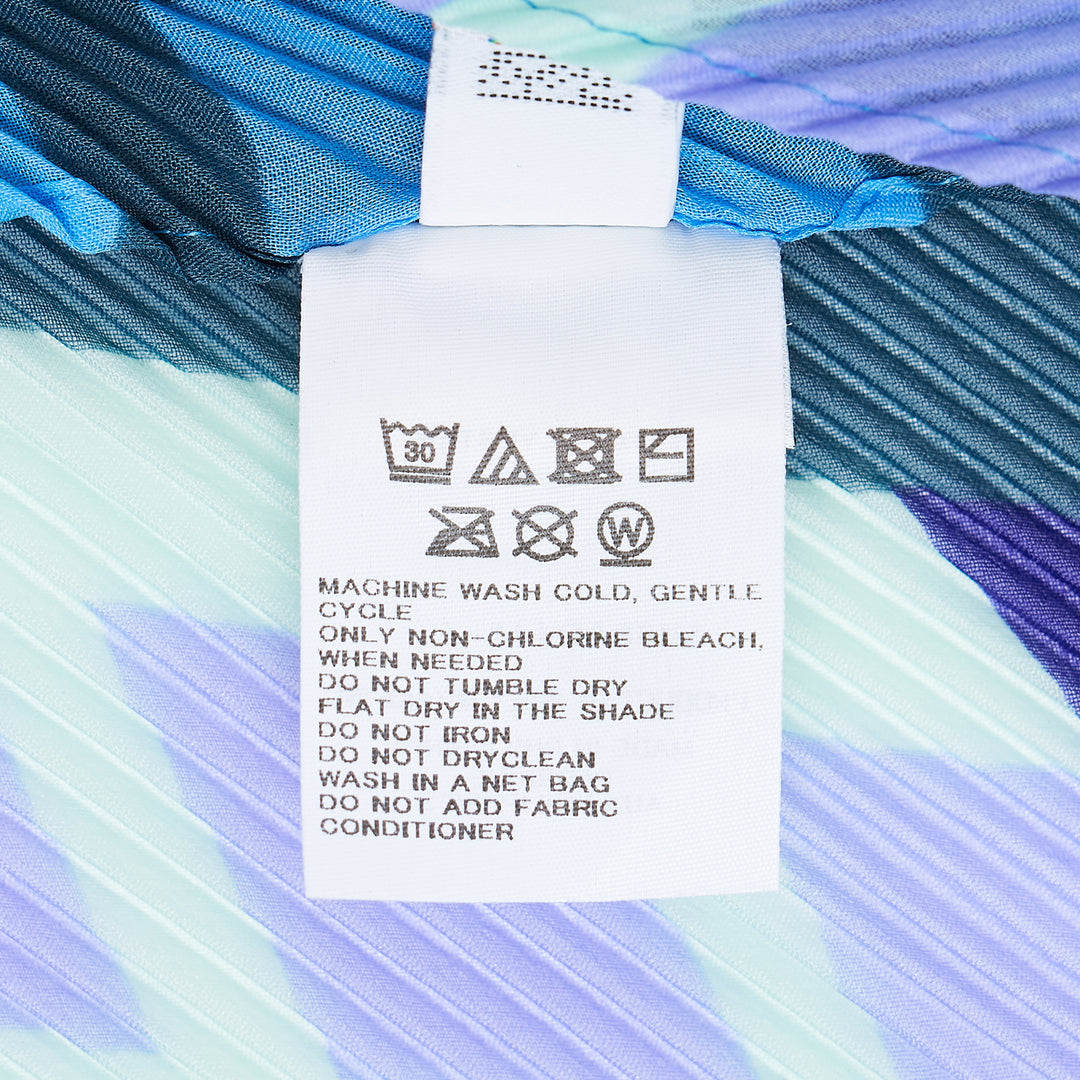 me Issey Miyake Building Pleats Stole in diamond silhouette featuring a tonal blue and violet geometric lattice pattern with botanical motifs and signature pleat construction