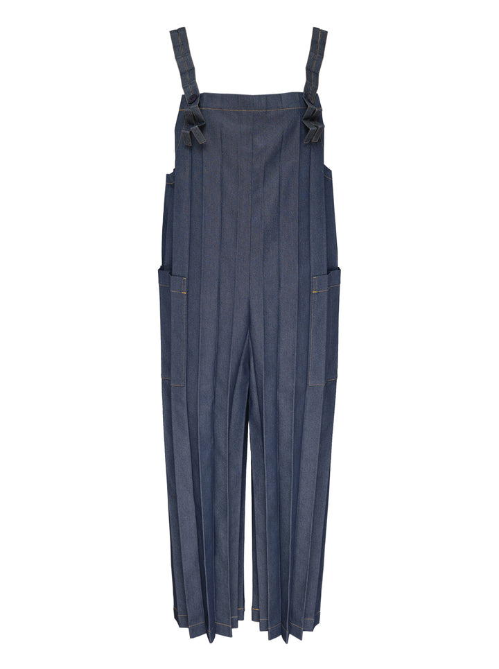 me Issey Miyake Denim Pleats Bottom jumpsuit in raw indigo denim, featuring deep vertical pleats, a square bib, knotted bow shoulder straps, patch hip pockets, and golden contrast topstitching