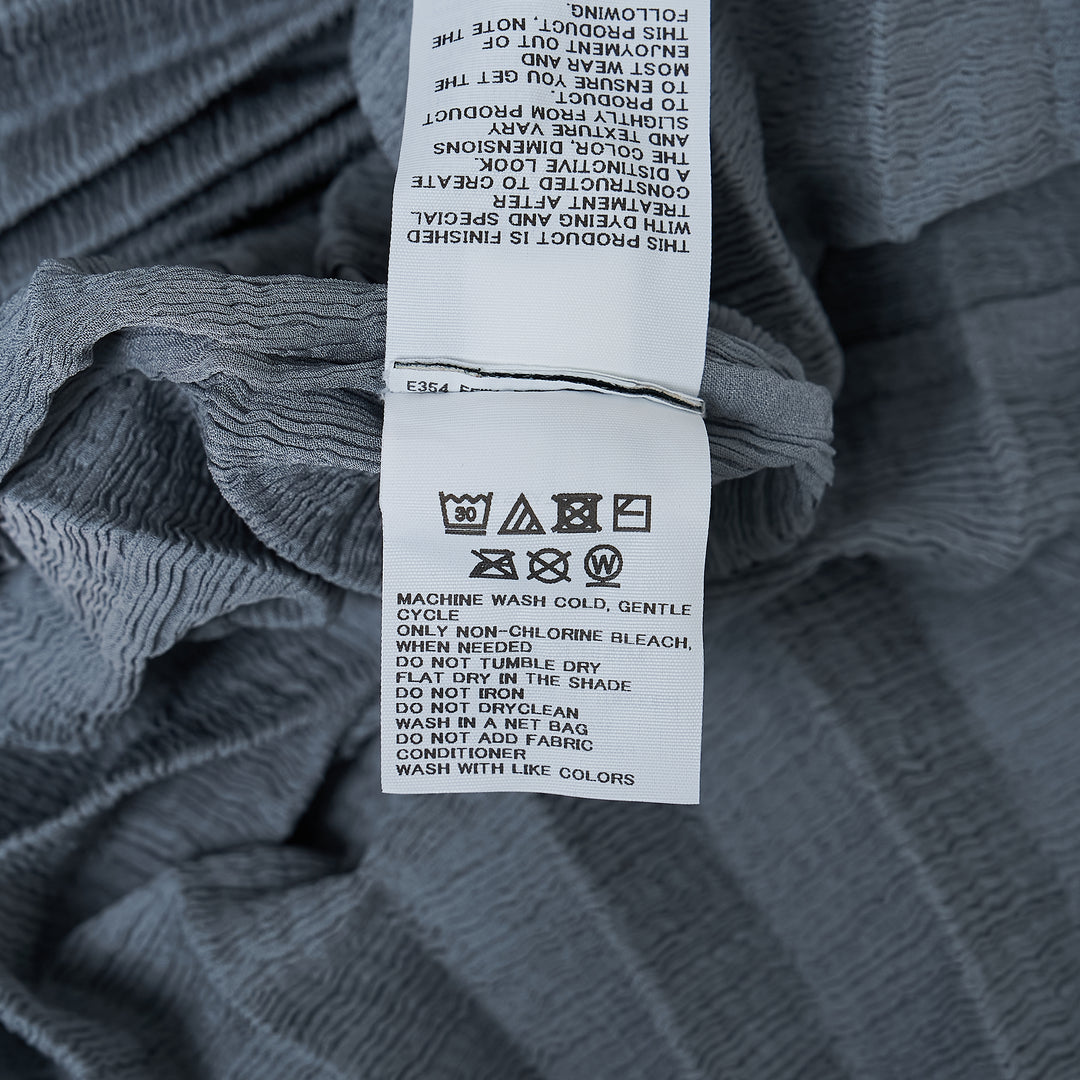 me Issey Miyake Accordion See-Through Crepe top in dusty blue, featuring horizontal accordion pleating, oversized boxy silhouette, elbow-length sleeves, and a gathered ruched hem, photographed flat on a white background