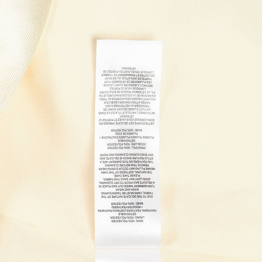 Self-Portrait pale yellow taffeta halter mini dress with feather and floral appliqué trim along the hem, displayed flat on a white background