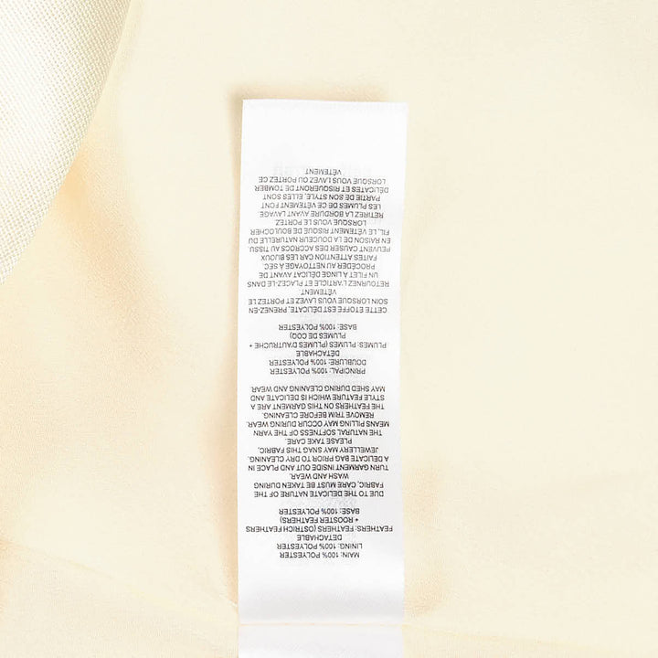 Self-Portrait pale yellow taffeta halter mini dress with feather and floral appliqué trim along the hem, displayed flat on a white background