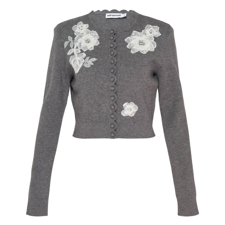 Self-Portrait grey knit cardigan with white 3D lace floral appliqués, scalloped neckline trim, and button-through front placket, laid flat on a white background