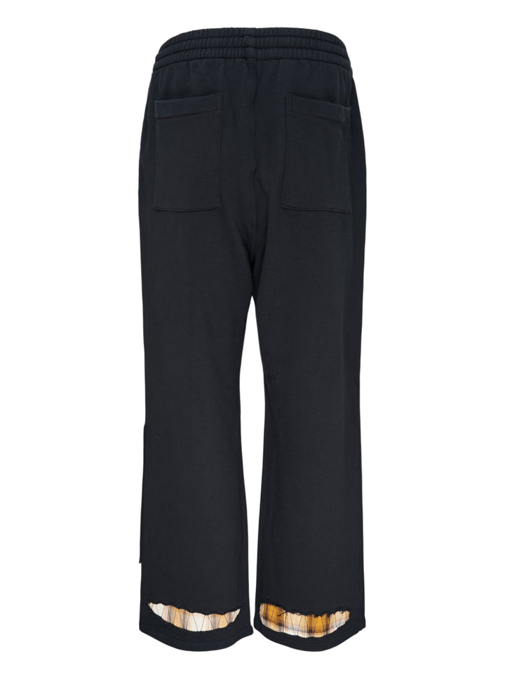 We11done Black Repaired Sweatpants with amber tartan plaid knee patch and embroidered logo, wide-leg relaxed fit, elasticated waistband, front view on white background - view 2