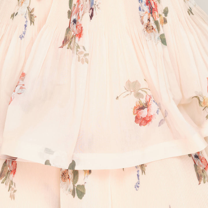 Zimmermann Pleated Tiered Midi Dress in blush floral print, featuring spaghetti straps, a pleated fitted bodice with bow detail, and four cascading ruffle tiers falling to a midi length