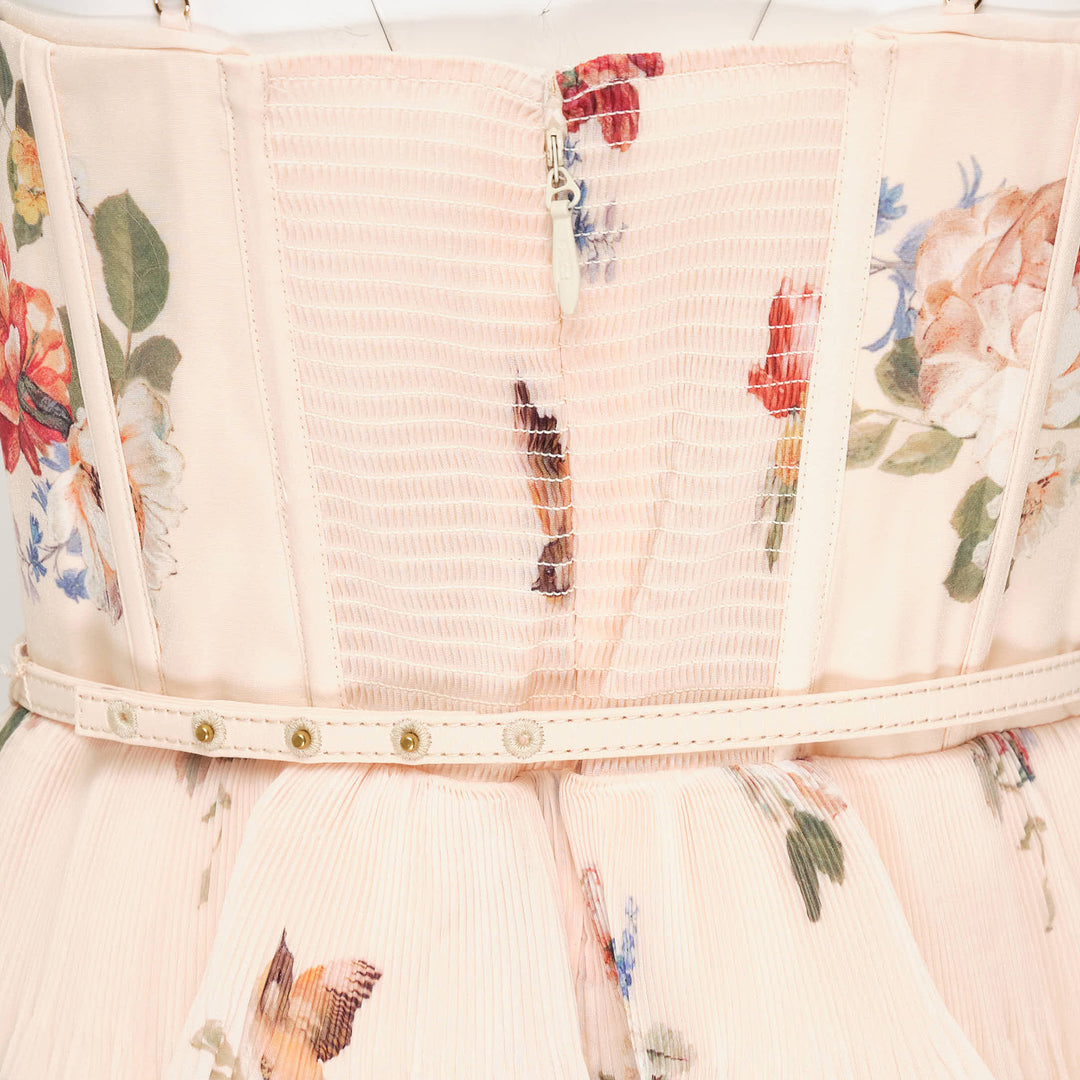 Zimmermann Pleated Tiered Midi Dress in blush floral print, featuring spaghetti straps, a pleated fitted bodice with bow detail, and four cascading ruffle tiers falling to a midi length