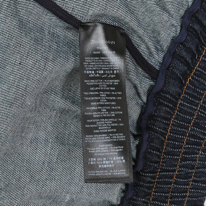 Zimmermann Denim Cape Top in dark indigo, back view, showing V-shaped gathered yoke, amber contrast topstitching, structured collar, and full sweeping hemline