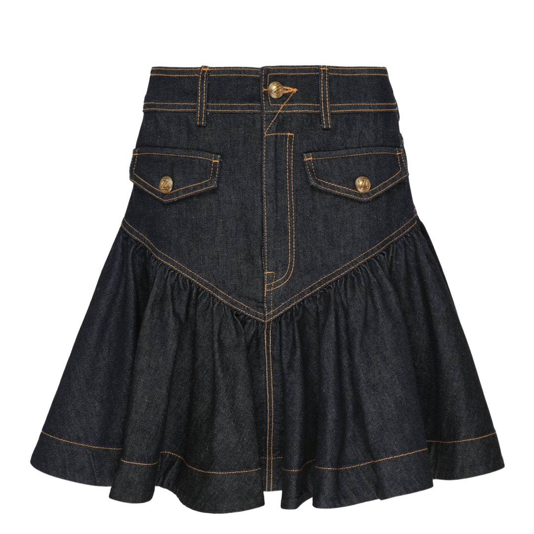Zimmermann Denim Frill Mini Skirt in dark indigo with orange contrast topstitching, chevron seam detail, front patch pockets with branded gold snap buttons, and a gathered ruffle hem