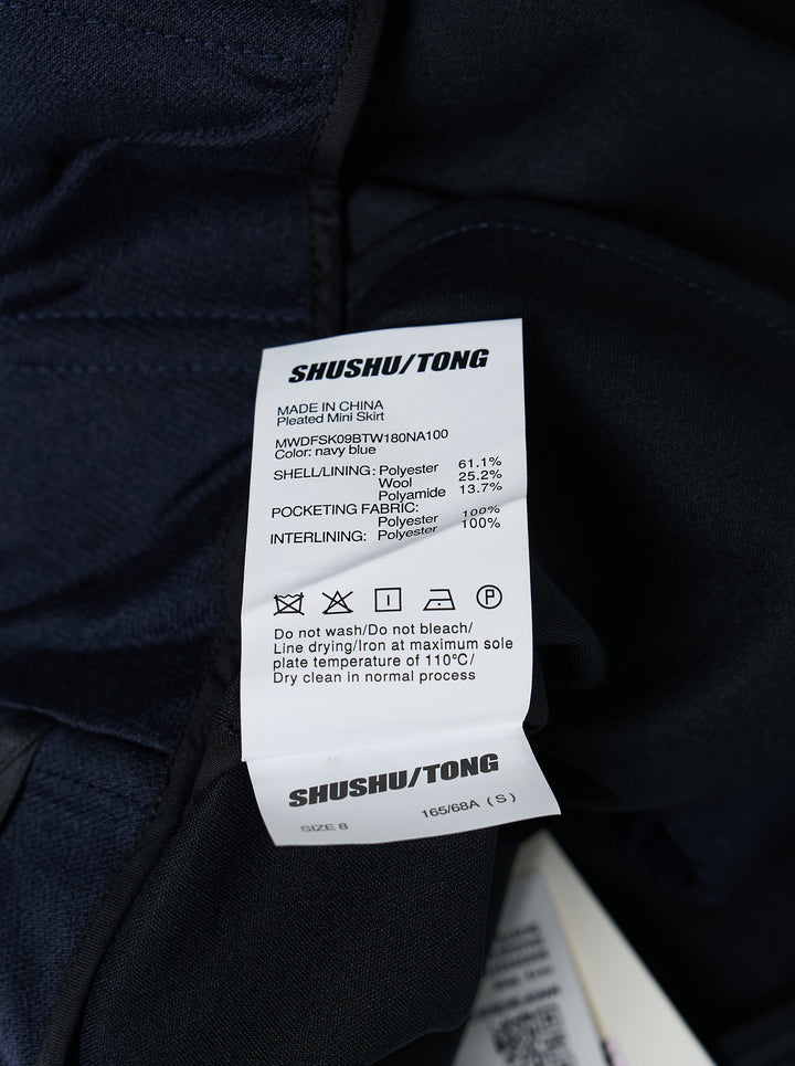 SHUSHU/TONG Pleated Mini Skirt in deep navy, featuring a fitted waistband, front pleat, and full voluminous flared hem, shown flat on a white background - view 3