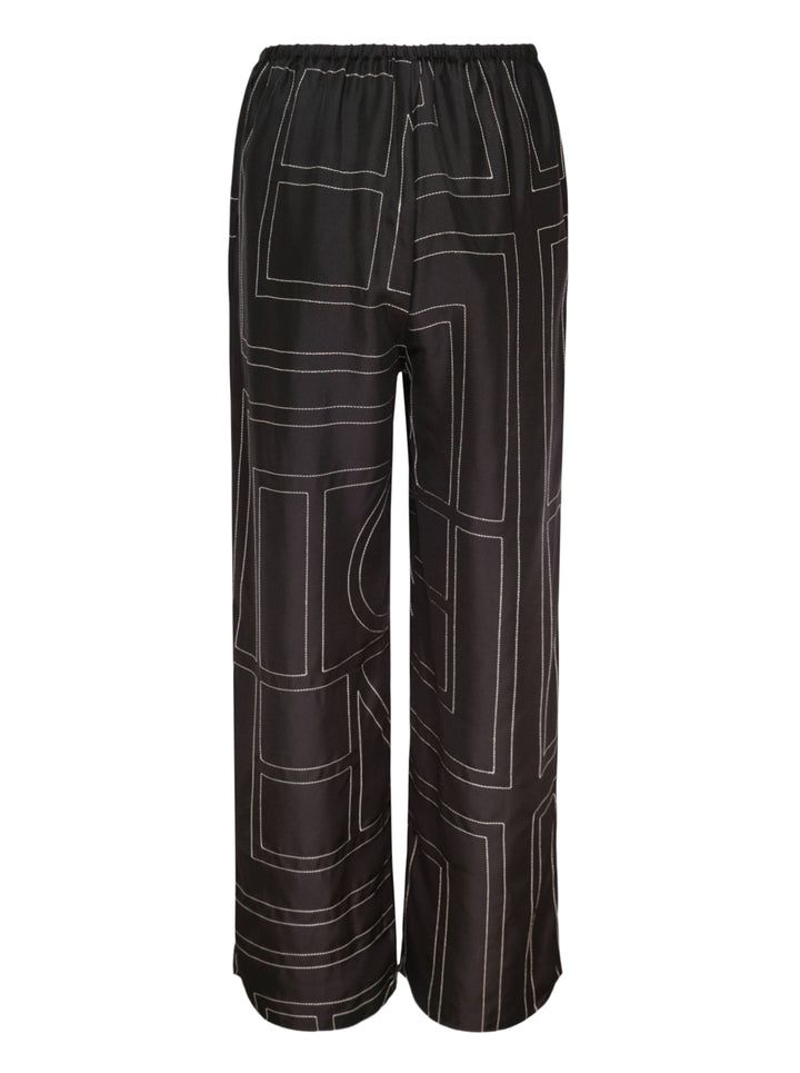 Toteme Monogram Silk Pyjama Pants in black with all-over contrast white stitched geometric panel print and elasticated waistband, wide-leg silhouette, flat lay view - view 2