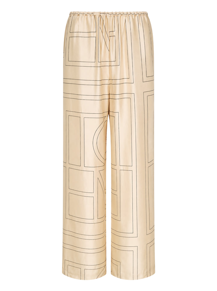 Totême Monogram Silk Pyjama Pants in champagne beige, featuring an all-over geometric monogram outline print, wide-leg silhouette, and elasticated waistband, displayed flat on a white background
