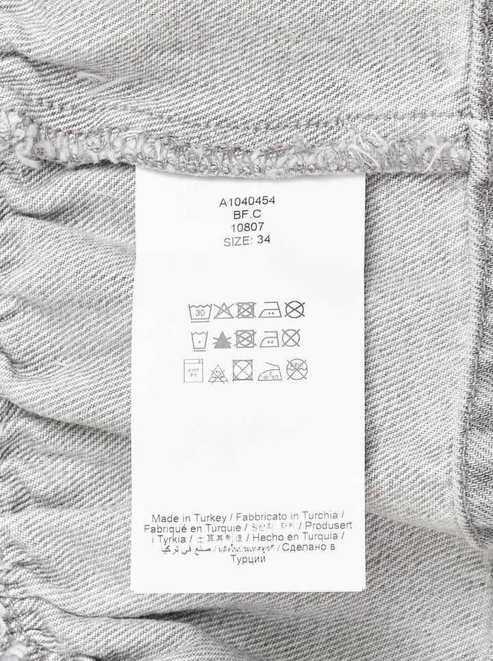 Ganni Rigid Denim Flounce Top in light grey wash, featuring a structured seamed bodice, three branded silver snap buttons at the centre front, wide shoulder straps, scoop neckline, and a gathered peplum ruffle hem - view 3