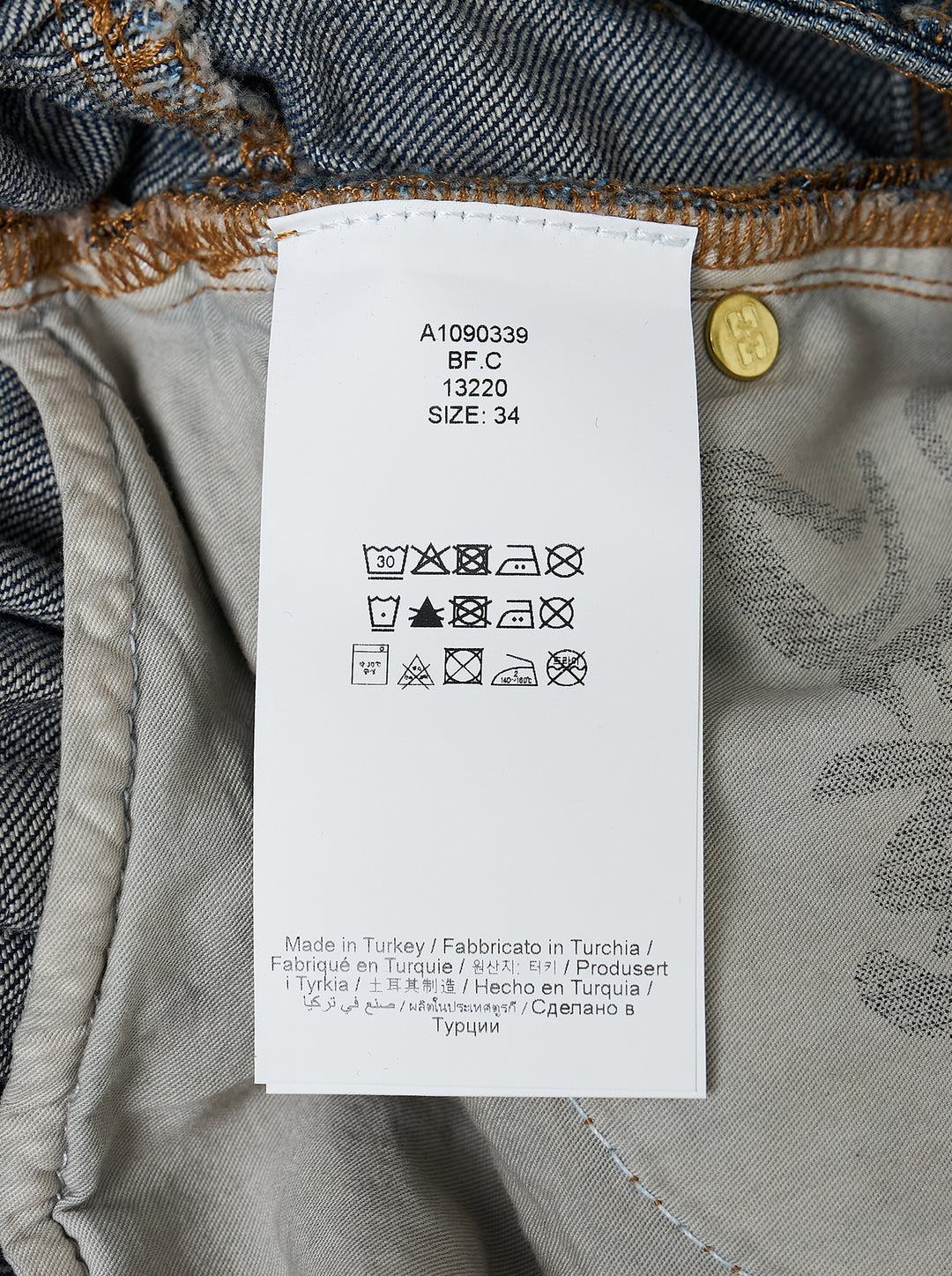 Ganni Slub Mix Denim Midi Skirt in washed indigo, featuring a high waistband, gathered tier seam, front patch pockets with gold rivets, and a full A-line silhouette with contrast orange topstitching - view 3
