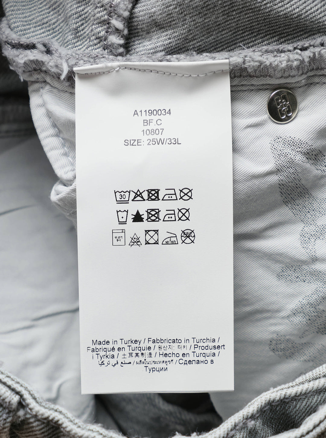 Ganni Rigid Denim Corset Jeans in light grey, featuring a high-rise waist, ruched corset seaming at the hip, and a wide balloon-leg silhouette tapering to small hem vents — front view on white background - view 3