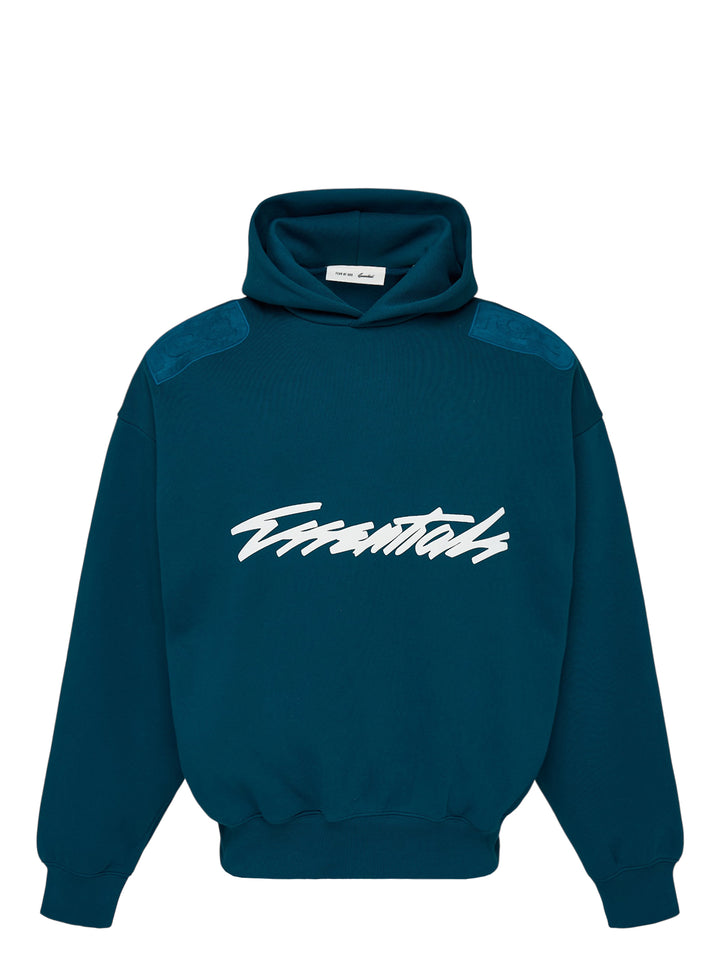 Fear of God Essentials Classic Raglan Hoodie in deep teal with white script logo across the chest and tonal textured shoulder panels