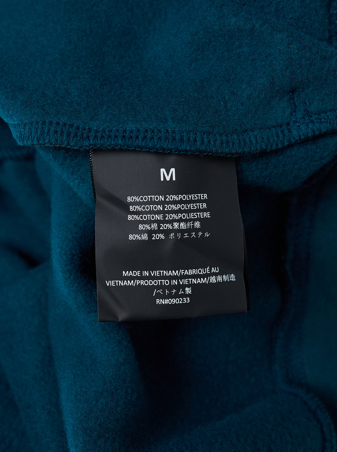 Fear of God Essentials Classic Raglan Hoodie in deep teal with white script logo across the chest and tonal textured shoulder panels - view 3