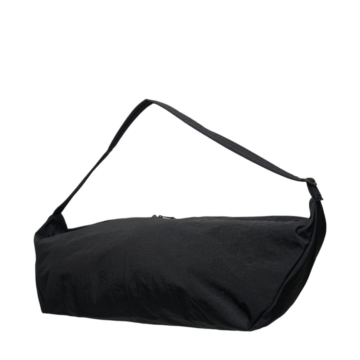 Fear of God ESSENTIALS x Eastpak Shell Bag Large in black, front view showing oversized body, wide shoulder strap, central zip closure, and co-branded woven label - view 2