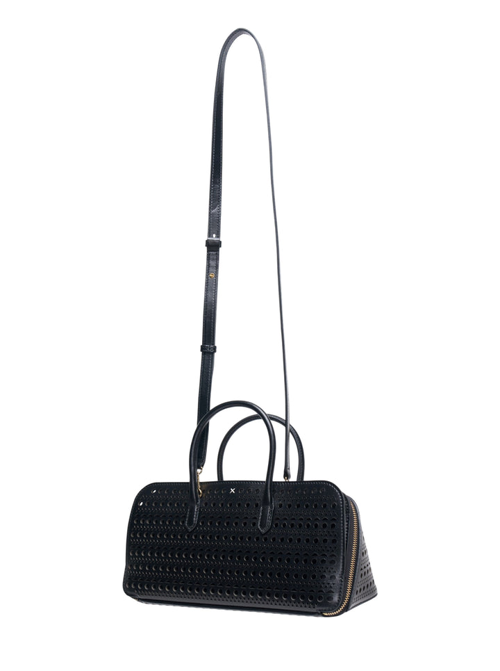 Alaïa Delta S top handle bag in black perforated leather with circular and triangular cutout pattern, dual rolled handles, gold-tone zip closure, and a long adjustable crossbody strap, shown on a white background - view 2