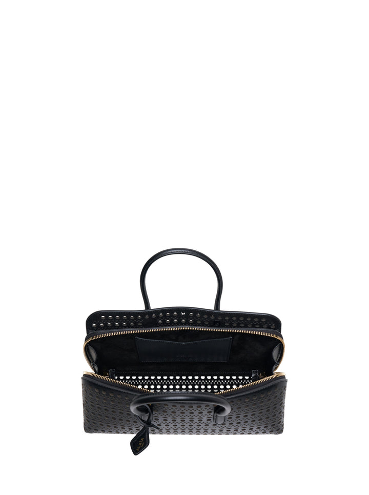 Alaïa Delta S top handle bag in black perforated leather with circular and triangular cutout pattern, dual rolled handles, gold-tone zip closure, and a long adjustable crossbody strap, shown on a white background - view 3
