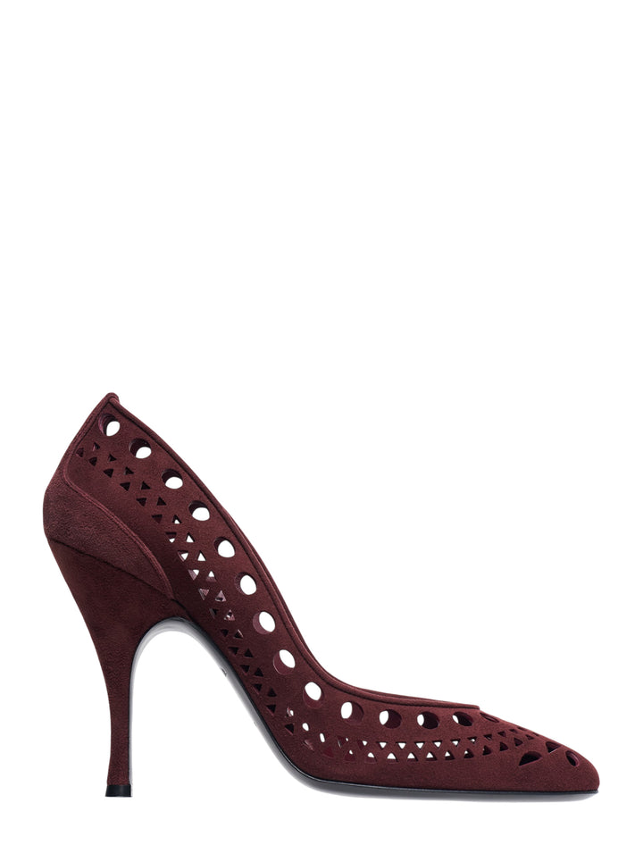Alaïa Vienne Suede Pumps 100 in deep burgundy with laser-cut circle and triangle perforations across the upper, pointed toe, and a slender 100mm stiletto heel, side profile view