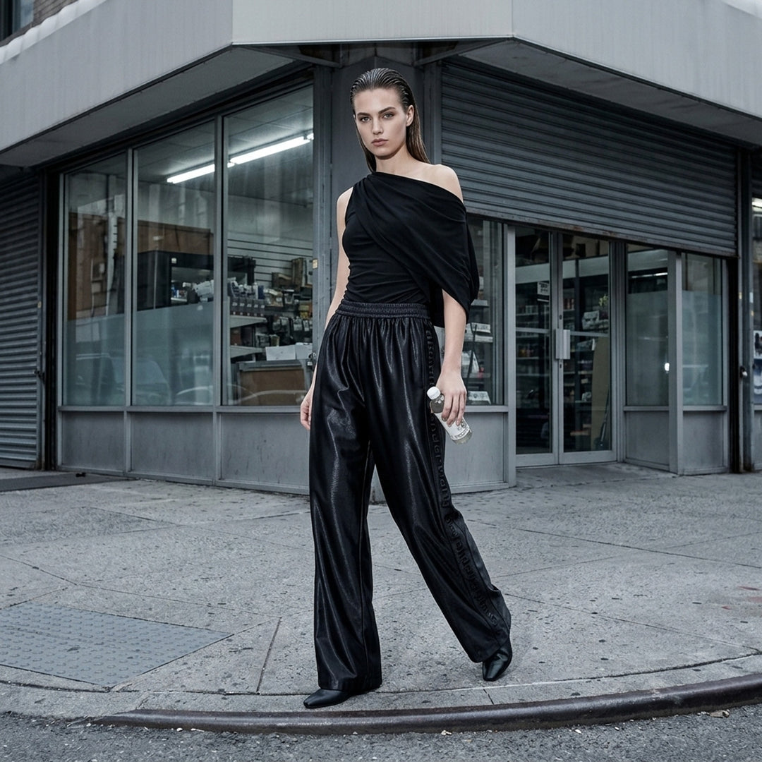 Alexander Wang mid-rise black glossy track pants with embossed side logo panels and elasticated waistband, shown from the front - lifestyle