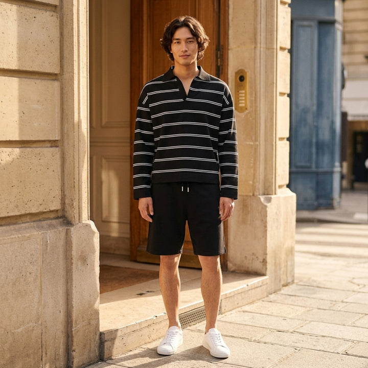 AMI Alexandre Mattiussi Long Sleeve Striped Polo in black with white horizontal stripes, featuring a spread collar, half-zip placket with heart logo pull, and ribbed cuffs - lifestyle