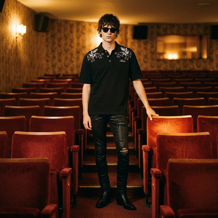 Black Amiri polo shirt with grey eagle and floral embroidery across the shoulders and an embroidered script logo on the chest - lifestyle