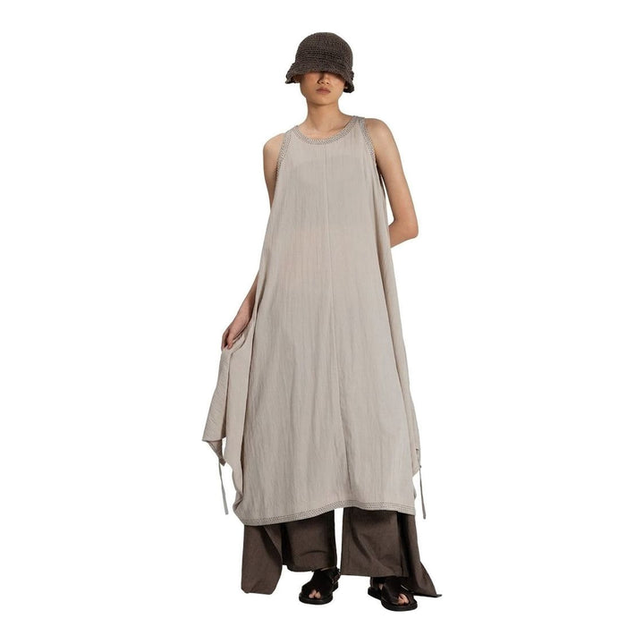 Model wearing an Anaabu black sleeveless midi dress with a voluminous A-line silhouette, asymmetric handkerchief hemline, and fine metallic stud trim at the neckline and hem - packshot