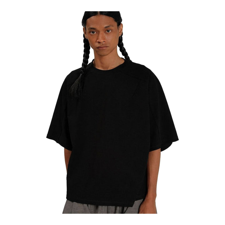 Model wearing the Anaabu Boxy Short Sleeve Tee in black — an oversized, dropped-shoulder silhouette styled over a taupe wide-leg trouser skirt - packshot