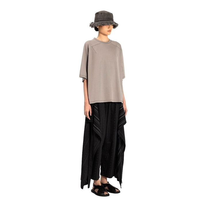 Model wearing the Anaabu Boxy Short Sleeve Tee in black — an oversized, dropped-shoulder silhouette styled over a taupe wide-leg trouser skirt - packshot