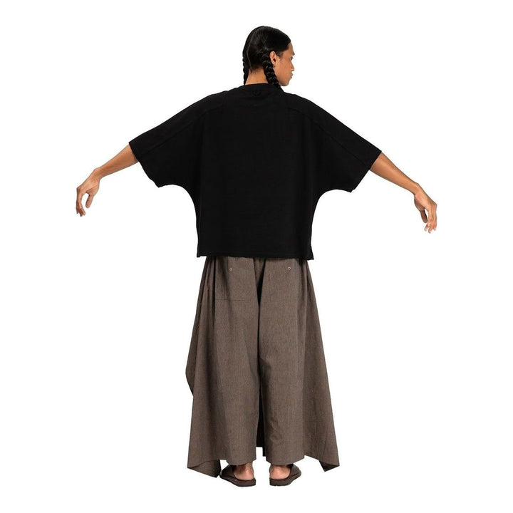 Model wearing the Anaabu Boxy Short Sleeve Tee in black — an oversized, dropped-shoulder silhouette styled over a taupe wide-leg trouser skirt - packshot