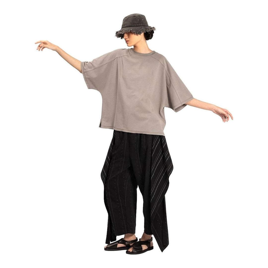 Model wearing the Anaabu Boxy Short Sleeve Tee in black — an oversized, dropped-shoulder silhouette styled over a taupe wide-leg trouser skirt - packshot