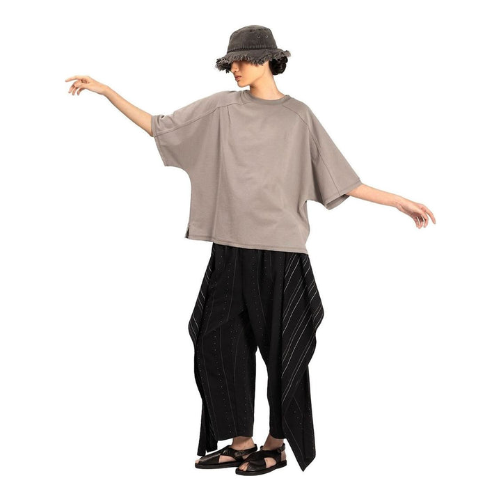 Model wearing the Anaabu Boxy Short Sleeve Tee in black — an oversized, dropped-shoulder silhouette styled over a taupe wide-leg trouser skirt - packshot