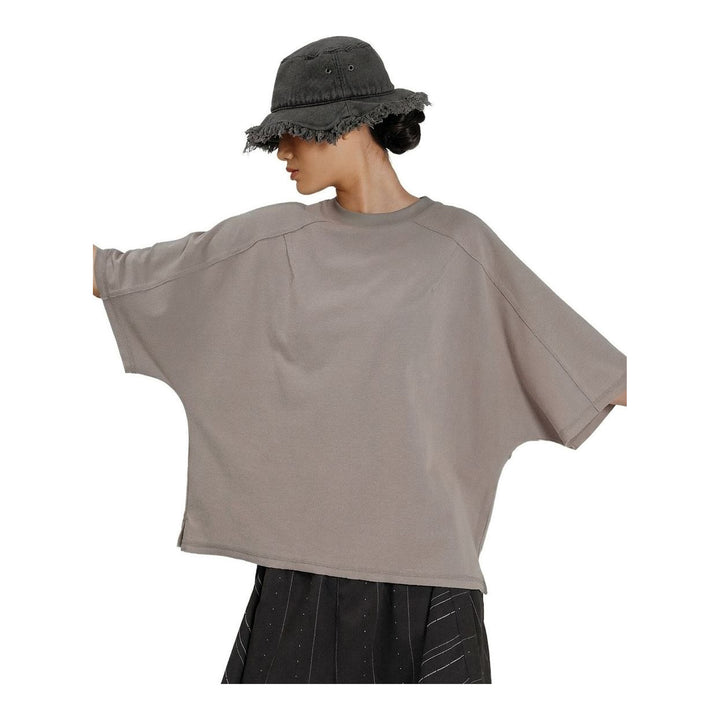 Model wearing the Anaabu Boxy Short Sleeve Tee in black — an oversized, dropped-shoulder silhouette styled over a taupe wide-leg trouser skirt - packshot