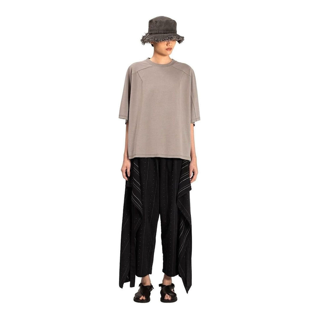 Model wearing the Anaabu Boxy Short Sleeve Tee in black — an oversized, dropped-shoulder silhouette styled over a taupe wide-leg trouser skirt - packshot