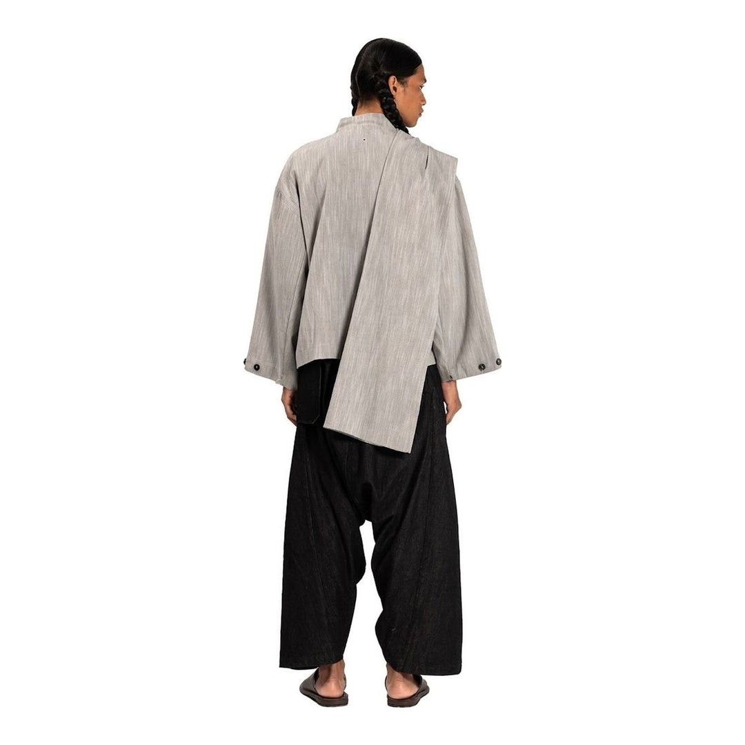 Model wearing the Anaabu Shawl Jacket in black — a draped wrap-style jacket with oversized shawl collar and self-tie belt, styled over a black turtleneck and olive wide-leg trousers - packshot