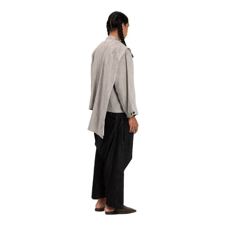 Model wearing the Anaabu Shawl Jacket in black — a draped wrap-style jacket with oversized shawl collar and self-tie belt, styled over a black turtleneck and olive wide-leg trousers - packshot