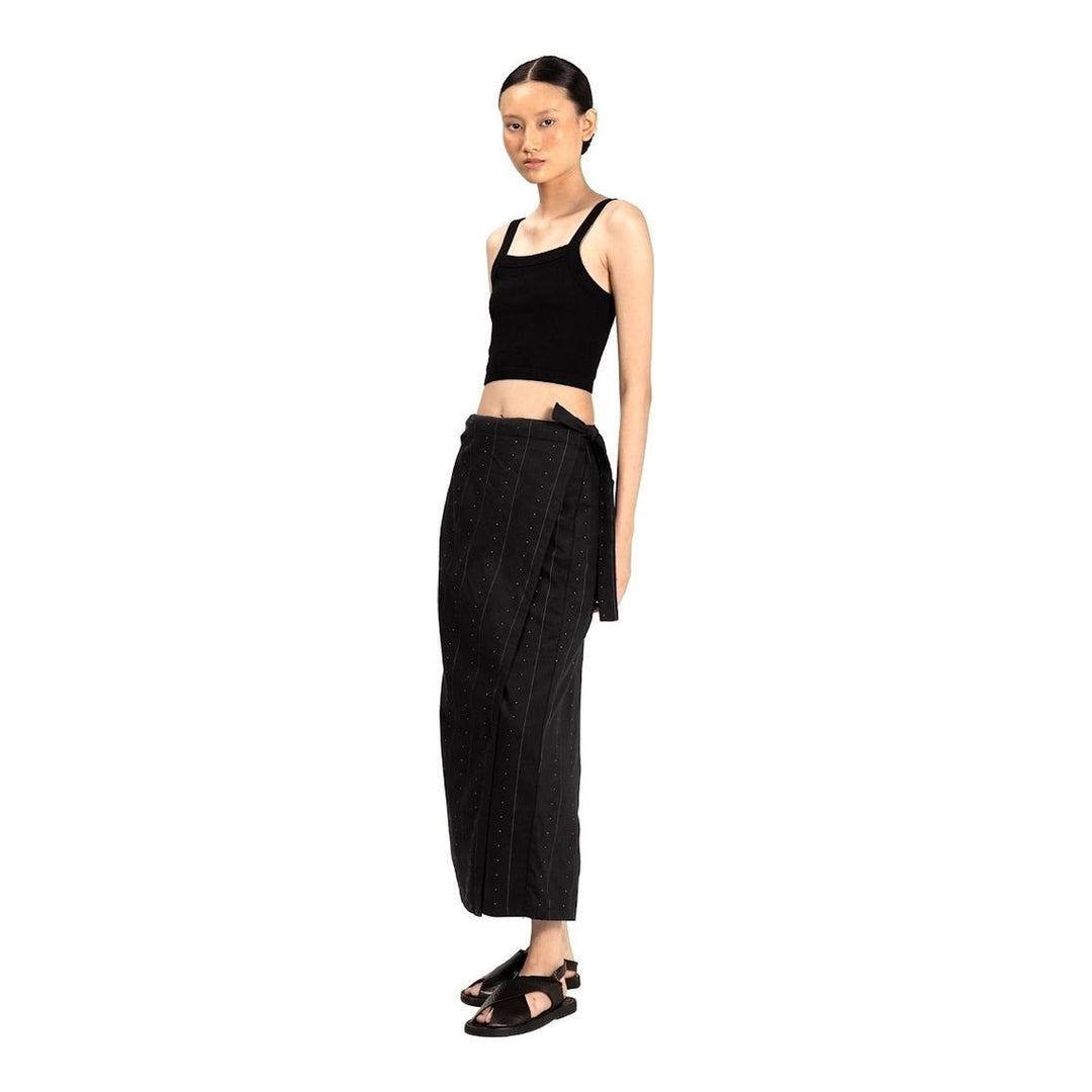 Model wearing Anaabu The Skants — black wide-leg cropped pants with large draped overlay panels featuring pinstripe and dot print, paired with a black square-neck crop top and leather sandals - packshot