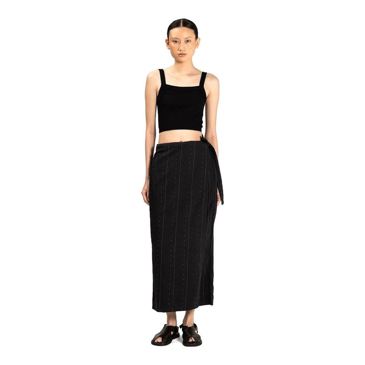 Model wearing Anaabu The Skants — black wide-leg cropped pants with large draped overlay panels featuring pinstripe and dot print, paired with a black square-neck crop top and leather sandals - packshot