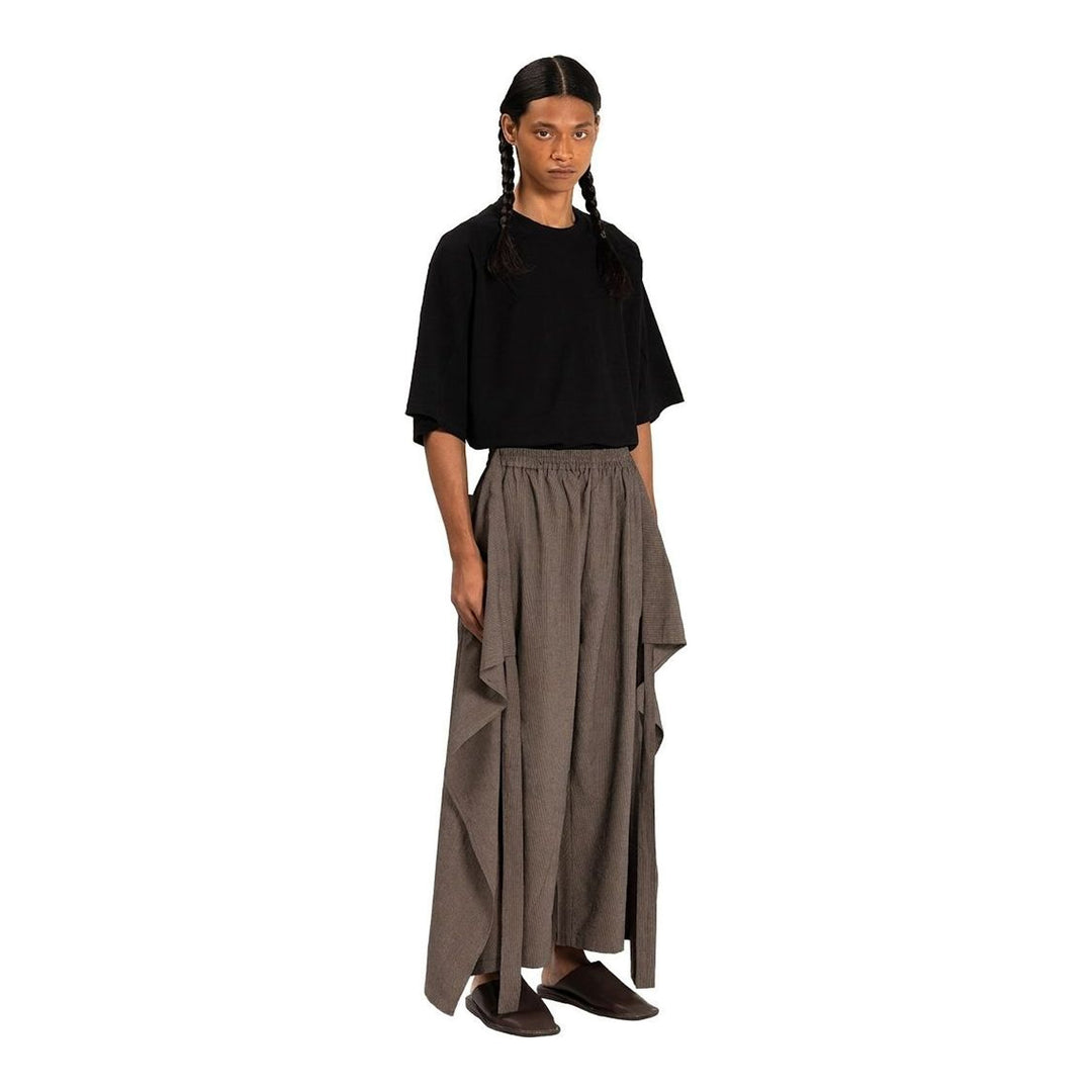Model wearing Anaabu The Skants — black wide-leg cropped pants with large draped overlay panels featuring pinstripe and dot print, paired with a black square-neck crop top and leather sandals - packshot