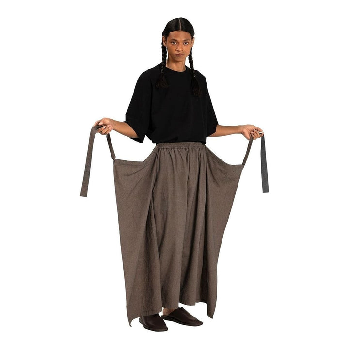 Model wearing Anaabu The Skants — black wide-leg cropped pants with large draped overlay panels featuring pinstripe and dot print, paired with a black square-neck crop top and leather sandals - packshot