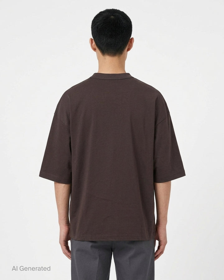 Comme des Garçons Homme Logo Tag Boxy Tee in dark brown with ribbed crewneck, dropped shoulders and wide short sleeves, shown flat from the front - back