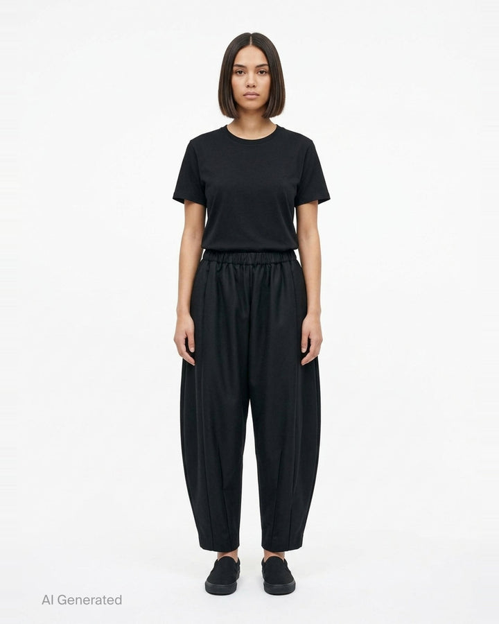 Comme des Garçons black rounded silhouette balloon-leg pants with elasticated waistband and structured vertical seaming, laid flat on white background - front