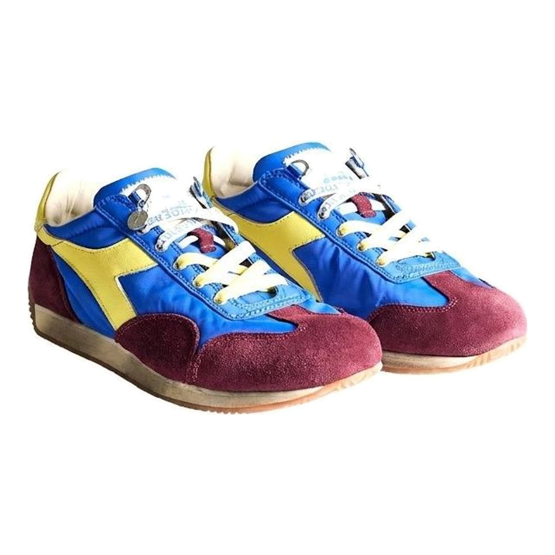 Diadora x JW Anderson retro nylon sneaker in blue with khaki suede overlays, coral laces, and a white Diadora logo stripe, set against a white background - packshot