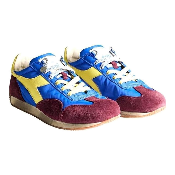 Diadora x JW Anderson retro nylon sneaker in blue with khaki suede overlays, coral laces, and a white Diadora logo stripe, set against a white background - packshot