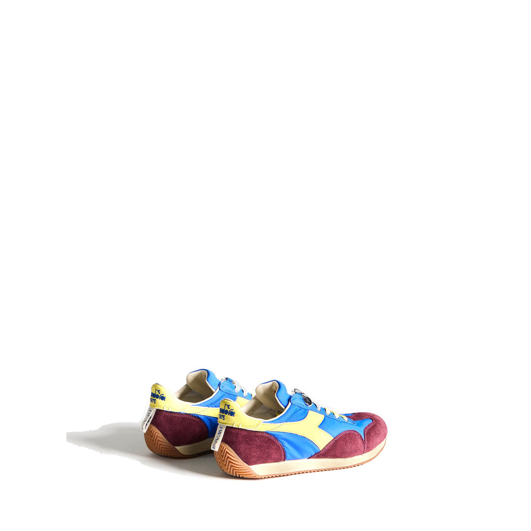 Diadora x JW Anderson retro nylon sneaker in blue with khaki suede overlays, coral laces, and a white Diadora logo stripe, set against a white background - packshot