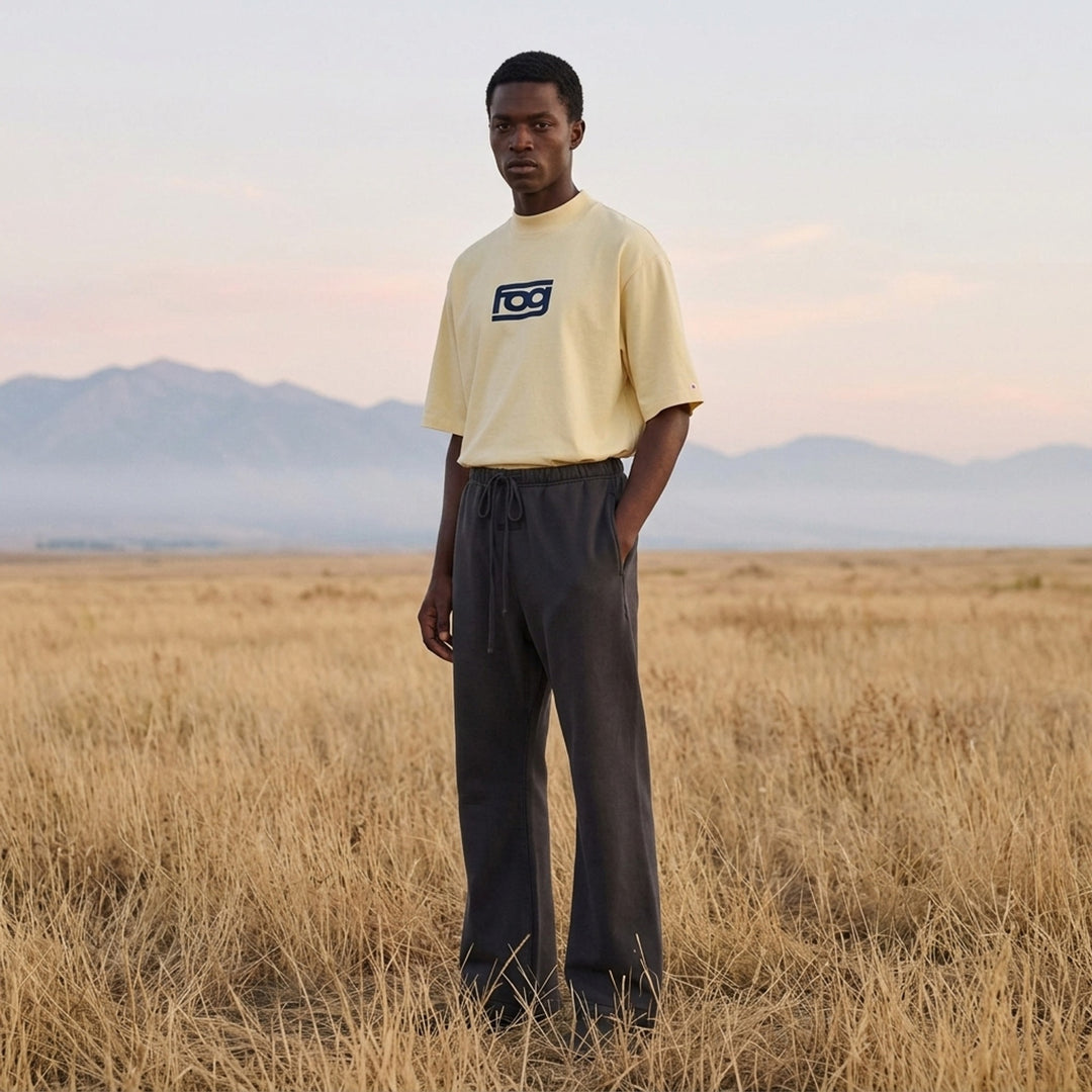 Fear of God ESSENTIALS Panelled Modern Tee in deep teal with a yellow logo graphic at the chest, shown from the front - lifestyle