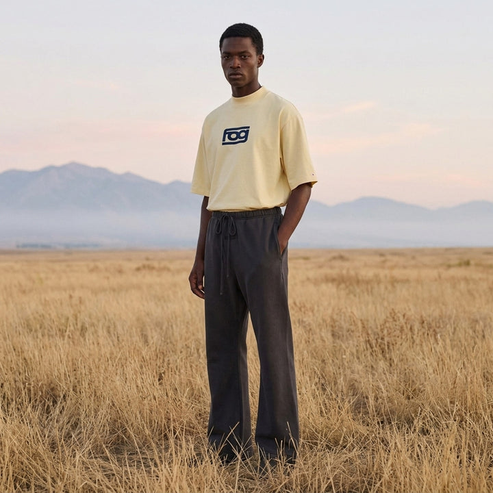 Fear of God ESSENTIALS Panelled Modern Tee in deep teal with a yellow logo graphic at the chest, shown from the front - lifestyle