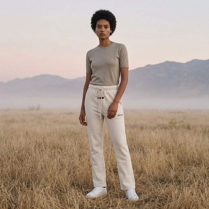 Fear of God ESSENTIALS women's slim sweatpants in heathered oat with drawcord waist, black logo tab and navy embroidered script logo - lifestyle