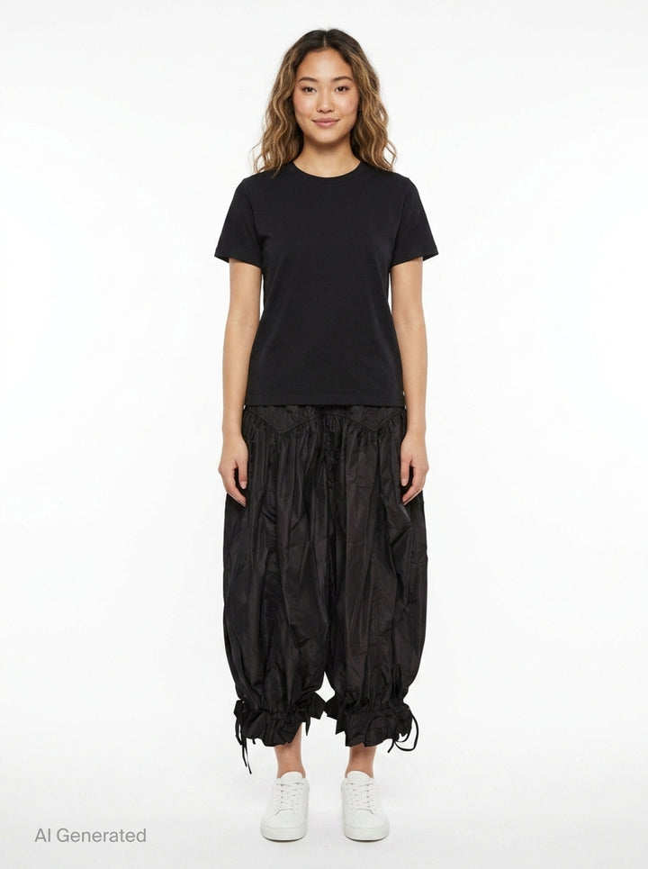 Ganni Flyweight Nylon Balloon Pants in black, featuring a smocked yoke, voluminous gathered body, and ruched tie ankles, displayed flat on a white background - front